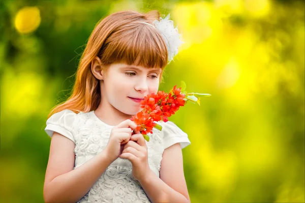 Portrait of a little girl outdoor in a garden smelling the flowe — Stock Photo, Image