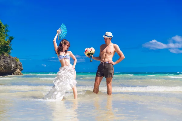 Happy bride and groom with a fan and a wedding bouquet having fu — Stock Photo, Image