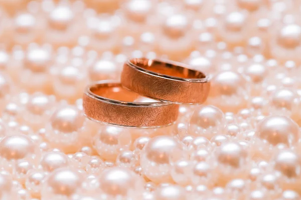 Pár zlatých snubních prstenů na scatterings perel. Svatba — Stock fotografie