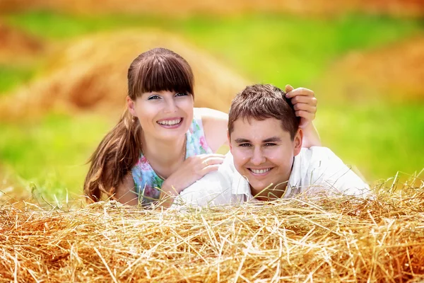 Любящая счастливая пара веселится в поле на стоге сена. Лето — стоковое фото