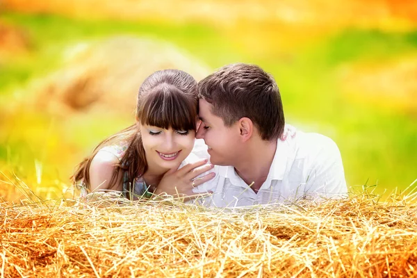 Liebevolles glückliches Paar, das sich auf einem Feld auf einem Heuhaufen vergnügt. Sommer — Stockfoto