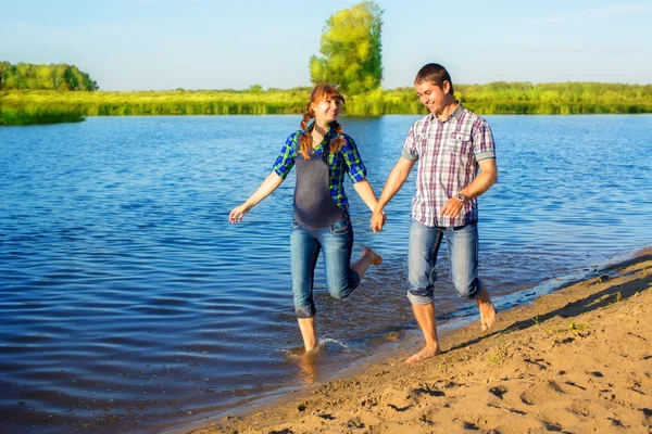 Glückliches und junges schwangeres Paar, das Spaß am Strand hat. Sommer — Stockfoto