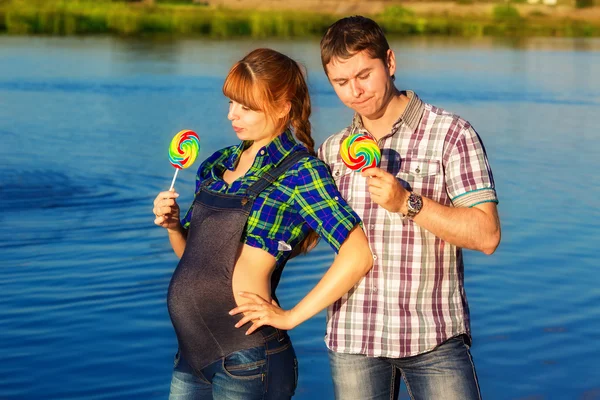 Glad och unga gravida par att ha kul på stranden. sommar — Stockfoto