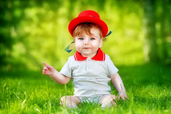 Happy little baby in red hat having fun in the park on solar gla — Stock Photo, Image