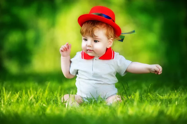 Happy little baby in red hat having fun in the park on solar gla — Stock Photo, Image