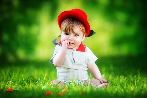 Happy little baby in red hat having fun in the park on solar gla — Stock Photo, Image