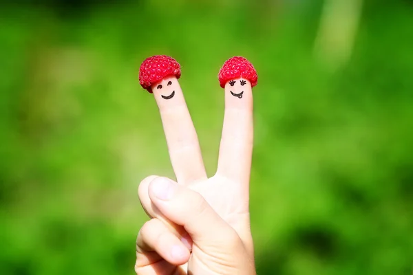 Happy couple fingers with raspberries and painted smiles — Stock Photo, Image