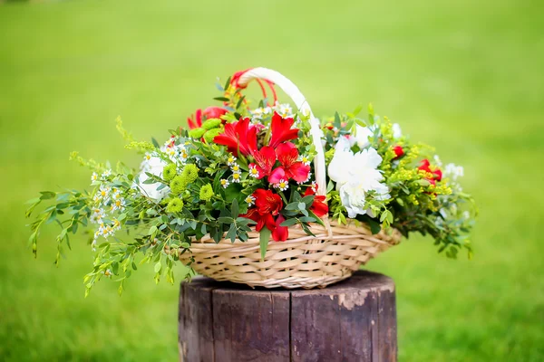 Arranjo floral com morangos em uma cesta na grama . — Fotografia de Stock