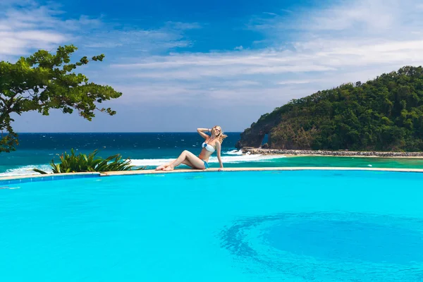 Giovane bella ragazza bionda è accanto alla piscina. Mare tropicale in — Foto Stock