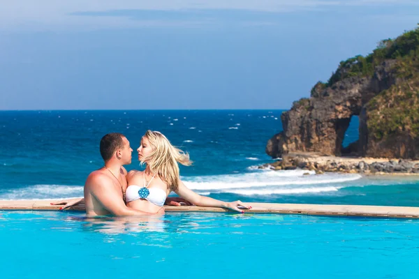 Giovane coppia felice amorevole in piscina. Mare tropicale nella parte posteriore — Foto Stock