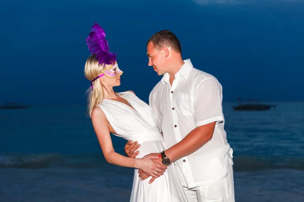 Bride and groom on a tropical beach with the sunset in the backg — Stock Photo, Image