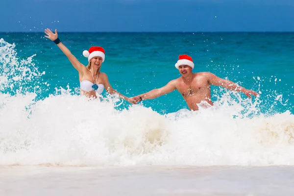 Young beautiful couple in love having fun in the waves dressed i — Stock Photo, Image