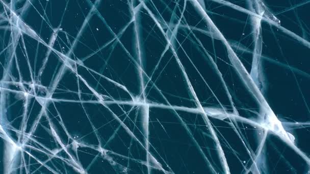凍った冬のバイカル湖のドローンからの空中視界. 深い亀裂が付いている青い透明な氷の上の眺め. 氷の自然な寒さの背景。 冬の抽象的な背景. — ストック動画