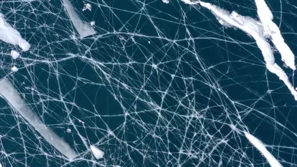 Luftaufnahme von einer Drohne auf dem zugefrorenen Baikalsee. Blaues, transparentes Eis mit tiefen Rissen von oben. Natürlicher kalter Hintergrund von Eis. Abstrakter Hintergrund im Winter. — Stockvideo
