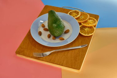 Tabakta yeşil avokado ve badem, mutfak tahtasında kurutulmuş portakal.