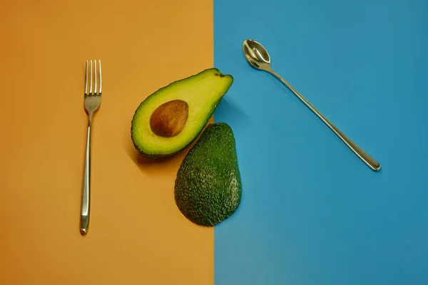 Vork Lepel Avocado Twee Delen Gesneden Een Achtergrond Van Pastelkleuren — Stockfoto