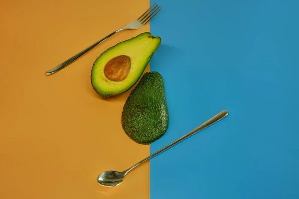 Vork Lepel Avocado Twee Delen Gesneden Een Pastelachtergrond — Stockfoto
