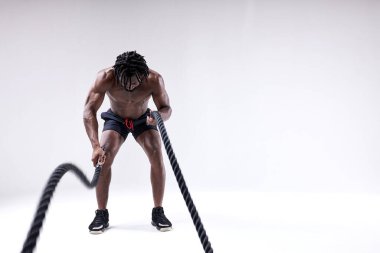 Beyaz arka planda izole edilmiş ağır iplerle çalışan kaslı adam..