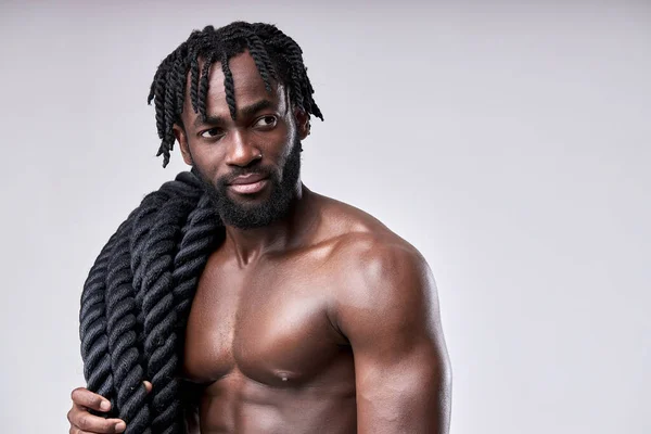 Joven sexy activo negro hombre va a entrenar con batalla cuerdas, mantenerse en forma, aislado — Foto de Stock