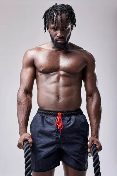 Joven sexy activo africano hombre va a entrenar con batalla cuerdas, mantenerse en forma, aislado — Foto de Stock