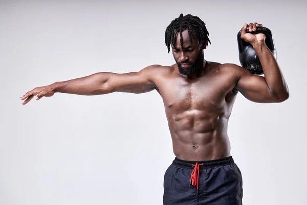 Afro jovem musculoso homem formação com kettlebell isolado no fundo branco. — Fotografia de Stock