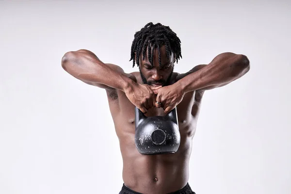 Αφρο-αμερικάνος γυμνόστηθος σηκώνει το kettlebell απομονωμένος σε λευκό φόντο στούντιο. — Φωτογραφία Αρχείου