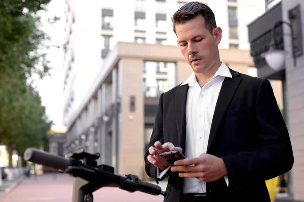 Mężczyzna płaci za wynajem skuterów za pomocą aplikacji mobilnej, stoisko ze smartfonem w mieście — Zdjęcie stockowe