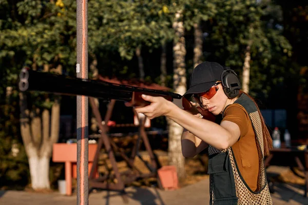 Fêmea em pé na atitude de mirar e olhar através da visão do rifle automático. — Fotografia de Stock