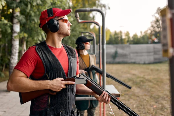 Vista laterale su maschio Guardando il lato dopo aver sparato. Armi da fuoco per tiro sportivo, hobby. — Foto Stock