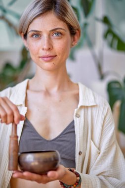 Tibet kâsesini tutan ve ellerine yapışmış çekici genç bir kadının yakın çekimi.