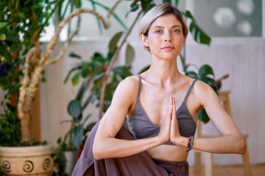 Esnek, güzel bir kadın egzersiz yapıyor, yerde meditasyon yapıyor, bacaklarını açıyor.