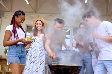 Bir grup arkadaş barbekü ızgarası açıyor ve akşam yemeği hazırlıyorlar.