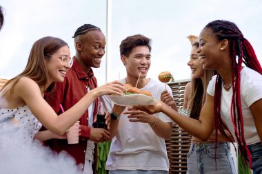 Bir grup mutlu arkadaş arka bahçedeki barbekü partisinde eğleniyor.