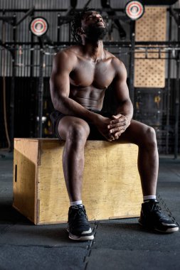 Yorgun ve bitkin Afrika kökenli Amerikalı erkek haç üzerine oturur ve dinlenir.