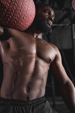 Sportif genç siyah adam bir egzersiz topuyla çekirdek egzersizleri yapıyor.