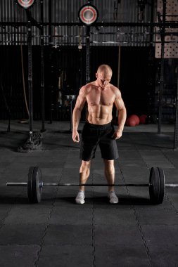 Beyaz tenli, terli, iri kaslı, ağır halter ağırlıklı bir adam.
