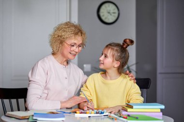 Bebek bakıcısı destek kızı masanın arkasında oturuyor, yaratıcı yeteneklerini geliştirmeye yardım ediyor.