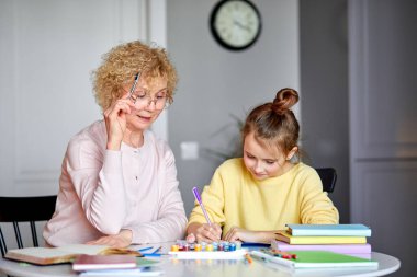 Yaratıcı aktivite. Mutlu yetişkin büyükanne ve küçük kız arkadaşlar masada otururlar.