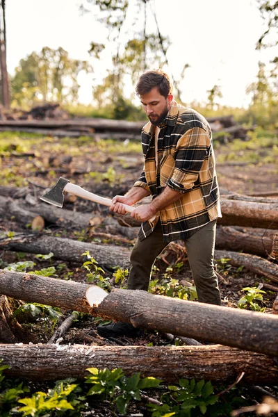 Homem sem barba com um machado corta um tronco, cortando árvores com machado. Técnica no trabalho. — Fotografia de Stock