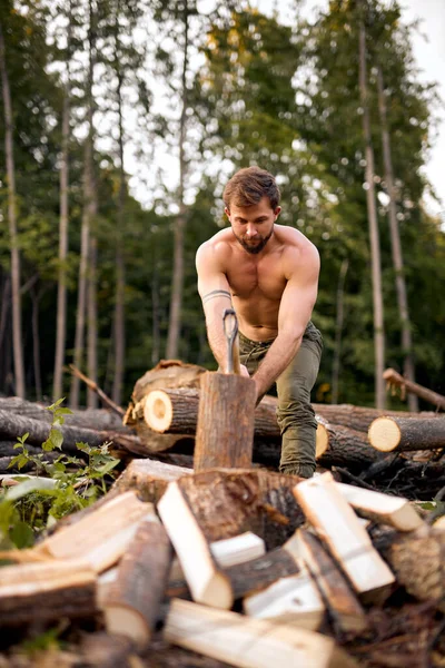 Shirtless Man usa machado para quebrar madeira. Preparação de madeira para acender um fogo — Fotografia de Stock