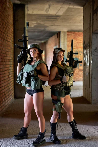 Två damer med gevär vid slagfältet, med fienden i övergiven byggnad — Stockfoto