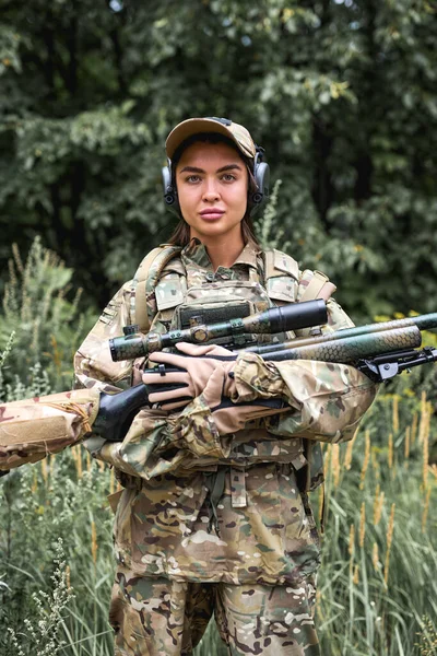 Retrato de mujer joven con arma en ropa militar al aire libre