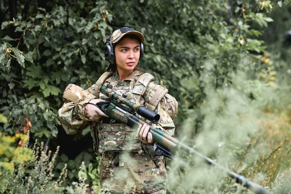 Femme confiante en équipement militaire et gilet pare-balles se tient dans le domaine de la forêt — Photo