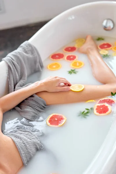 Donna snella irriconoscibile gode di bagno con latte e succosi frutti esotici. cura del corpo. — Foto Stock