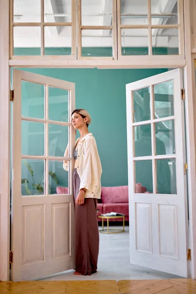 Femme caucasienne réfléchie debout près de la porte posant, à la maison seule, portrait — Photo