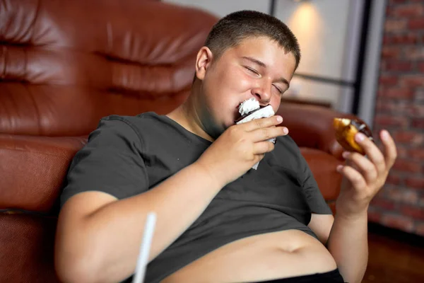 Jonge tiener jongen eet donut en cake thuis. Lekker eten voor kinderen — Stockfoto