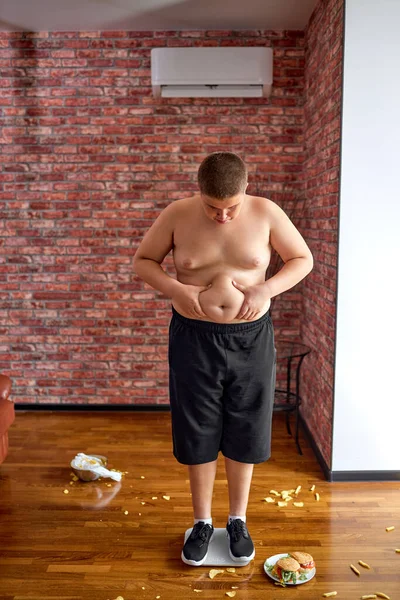 Obese jongen teleurgesteld na het wegen en ontdekte dat hij aangekomen gewicht. — Stockfoto