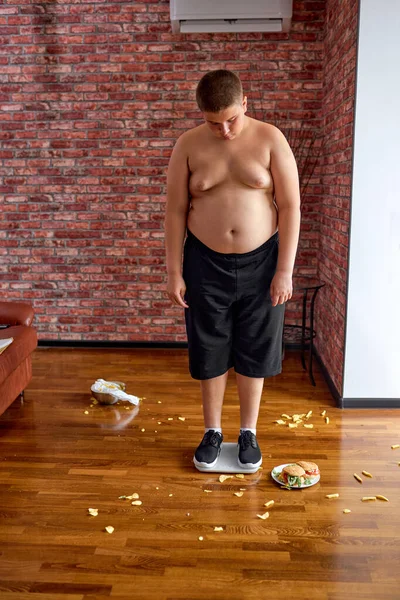 Chlapec dospívající na váhové stupnici pro kontrolu váhy. Dieta, koncepce obezity — Stock fotografie