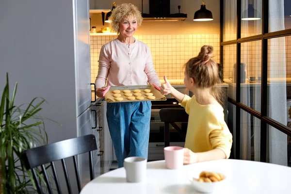 Αξιολάτρευτο κορίτσι δείχνει αντίχειρες μέχρι τη γιαγιά έρχονται με μαγειρεμένα μπισκότα — Φωτογραφία Αρχείου