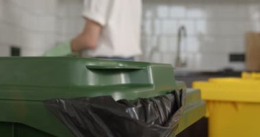Daha fazla işlem için ev atıklarının sıralanması. Kadın şişeyi yeşil kutuya attı.